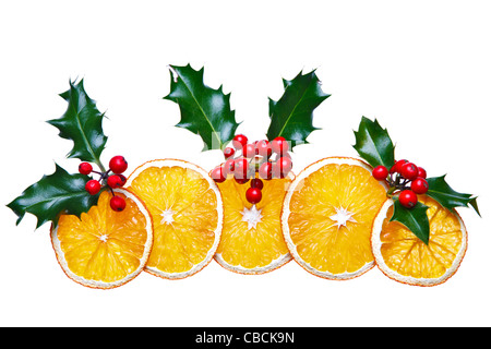 Photo of dried orange slices and holly with red berries arranged into a decorative Christmas image, Foto Stock