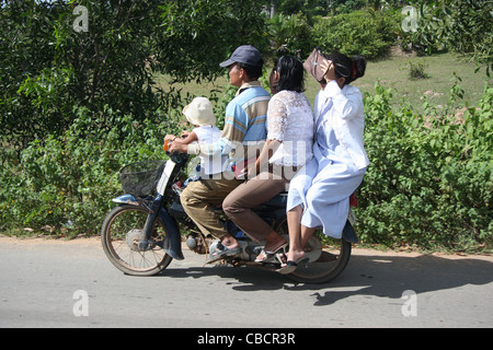 Quattro persone compreso il giovane figlio sono in sella a una motocicletta a Siem Reap, Cambogia durante un raduno politico Foto Stock