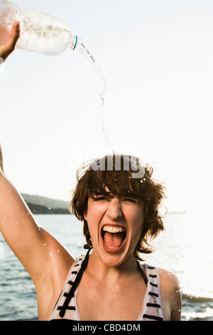 Donna versando acqua su se stessa a beach Foto Stock