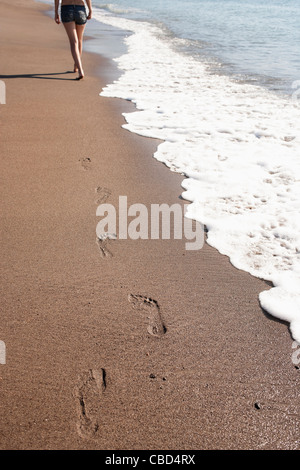 Donna di impronte sulla spiaggia Foto Stock