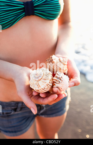 Donna che mantiene conchiglie sulla spiaggia Foto Stock