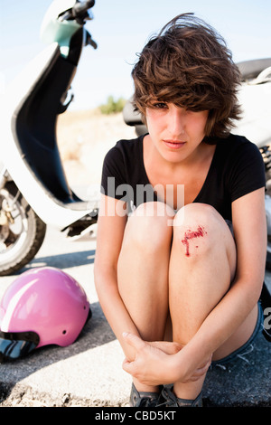 Donna con scooter infermieristica ginocchio raschiata Foto Stock