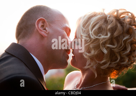 Felice sposa e lo sposo kissing all'aperto al tramonto Foto Stock