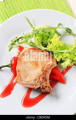 Arrosto di maiale tagliate e pepe rosso guarnita con insalata verde Foto Stock