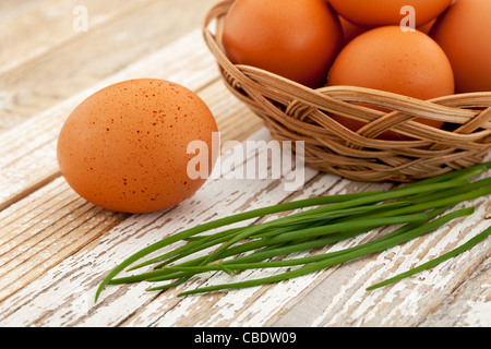 Motivo di Pasqua - marrone le uova di gallina in un cestello e verde erba cipollina su un bianco grunge superficie in legno Foto Stock