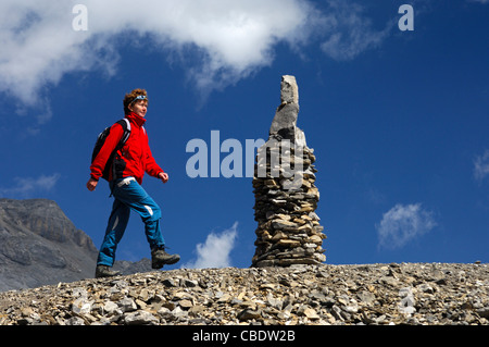 Escursionista passando da un tumulo come segno direzionale e guida di orientamento in un roccioso, trailless area alpina, Vallese Svizzera Foto Stock