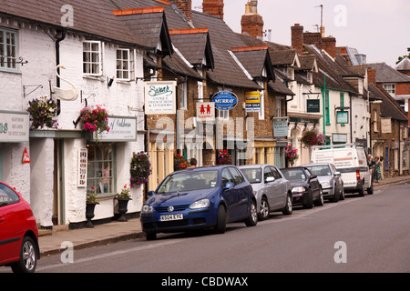 Storico negozio fronti, segni e automobili parcheggiate lungo il centro dello shopping, Mill Street, Oakham, Rutland, England, Regno Unito Foto Stock