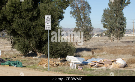 Cestino accanto ad una strada sterrata accanto a un nessun segno di dumping Foto Stock