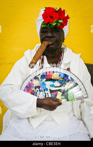 Donna cubana che indossa un Santeria abito bianco di fumare un sigaro di grandi dimensioni La Habana Vieja La Habana Cuba Foto Stock