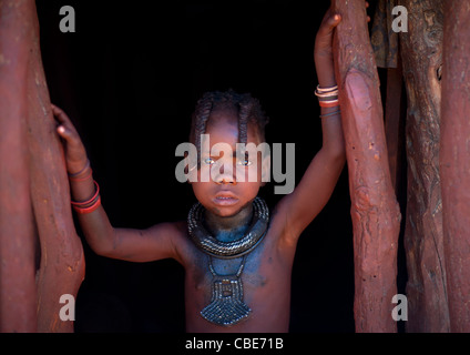 Ragazza Muhimba all'ingresso del suo rifugio, villaggio di Elola, Angola Foto Stock