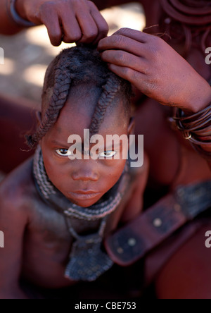 Muhimba giovane ragazza avente i suoi capelli essendo fatto villaggio di Elola, Angola Foto Stock