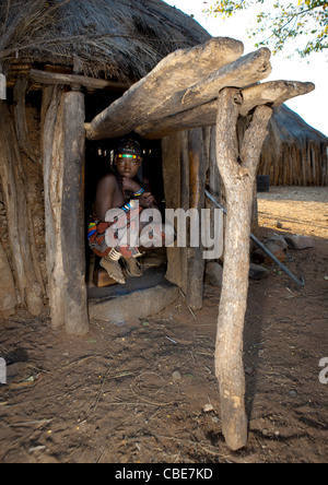 Ragazza Mucawana accovacciato in ingresso del suo rifugio, villaggio di Mahine, Angola Foto Stock