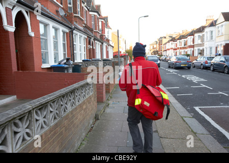 Portalettere consegna la posta in una fredda mattina di dicembre cricklewood nel nord di Londra England Regno Unito Regno Unito Foto Stock