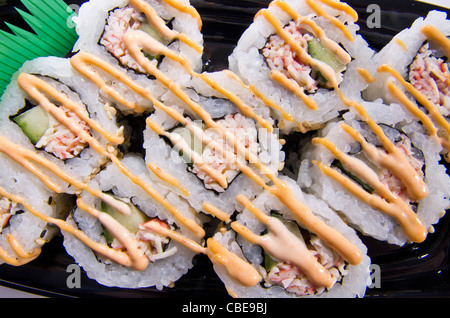 Close up di piccante california sushi rotoli su una piastra nera. Foto Stock