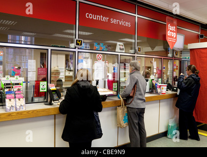 Ufficio postale Regno Unito; persone al banco all'interno di un ufficio postale inglese, Suffolk Regno Unito Foto Stock