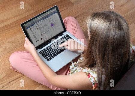 Ragazza adolescente usando il suo computer portatile con facebook pagina aperta. Foto Stock