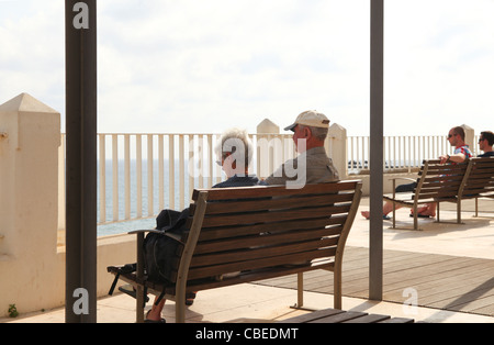 Coppia di anziani su una panchina che guarda sul mare in Portogallo Foto Stock