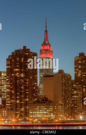 L'Empire State Building, illuminato in rosso per la Giornata Mondiale dell Aids e di altri edifici sul lato est al crepuscolo in New York City. Foto Stock