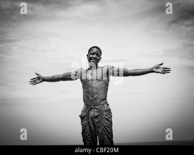 Uomo che fa la croce cristiana con le sue braccia sulla spiaggia, Benguela, Angola Foto Stock