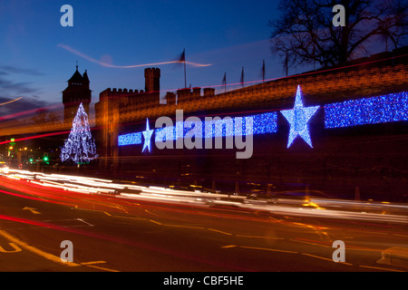 Il Castello di Cardiff durante la notte con le luci di Natale / decorazioni e percorsi di traffico in primo piano Cardiff South Wales UK Foto Stock