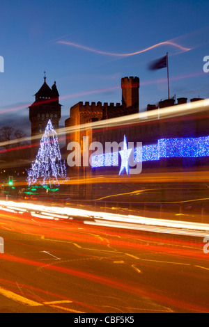 Il Castello di Cardiff durante la notte con le luci di Natale / decorazioni e percorsi di traffico in primo piano Cardiff South Wales UK Foto Stock