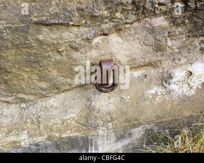 Vecchio arrugginito anello metallico fissato a una parete per l'equilibrio e la sicurezza. Foto Stock