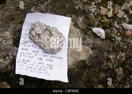 Messaggio ebraico scritto su carta appesantito con una pietra in un cimitero ebreo a Cracovia in Polonia Foto Stock