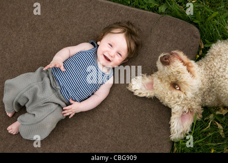 Una bambina e cane giacente al di fuori Foto Stock