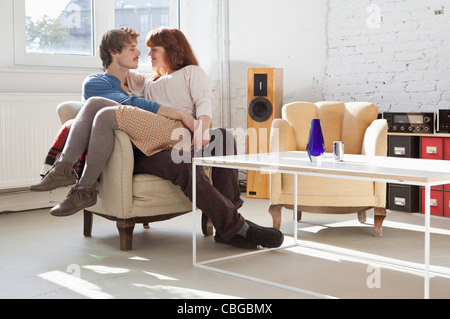 Una giovane donna comodamente seduto nel suo fidanzato la lap Foto Stock