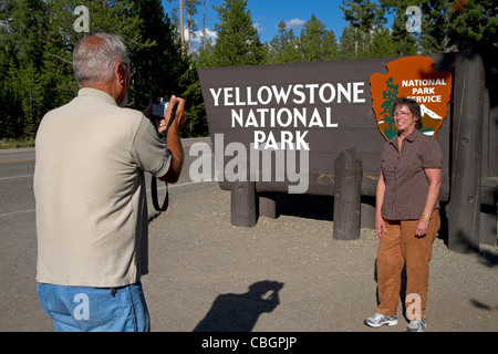 I turisti scattare una foto di fronte al Parco Nazionale di Yellowstone entrata SEGNO, West Yellowstone, Montana, USA. Foto Stock