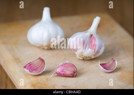 Bulbi di aglio e chiodi di garofano su un tagliere di legno Foto Stock