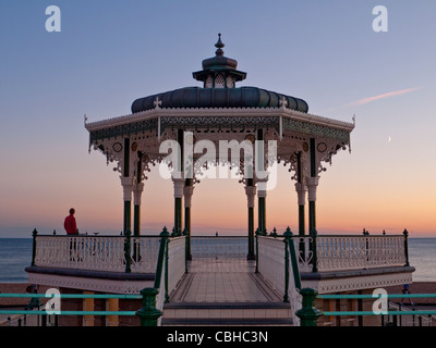 BRIGHTON Victorian Bandstand sul lungomare al tramonto con lone figura ammirando la vasta seascape visualizza Brighton SUSSEX REGNO UNITO Foto Stock