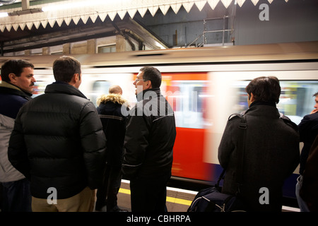 Persone in piedi sulla piattaforma come velocità del treno con la metropolitana di Londra England Regno Unito Regno Unito Foto Stock