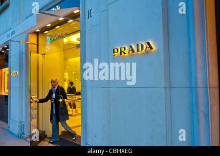 Parigi, Francia, Shopping di abbigliamento di lusso, Negozio Prada, ingresso donna in partenza, Avenue Montaigne, negozio porta anteriore, etichette modalità, luci Foto Stock