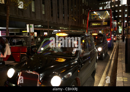 Fila di black london taxi I taxi e bus di notte bloccati nel traffico su strada per lo shopping in centro a Londra England Regno Unito Regno Unito Foto Stock