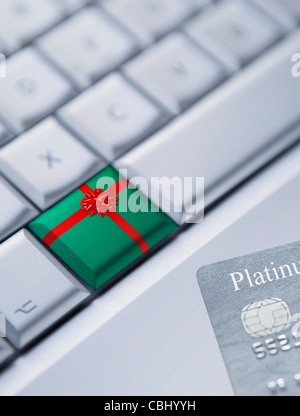 Dettaglio di una tastiera con una chiave avvolto come un regalo di Natale e una carta di credito presso l'angolo inferiore destro. Foto Stock