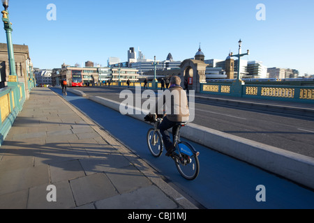 Ciclista utilizzando dei " commuters " barclays biciclette ciclo sulla pista ciclabile su Southwark Bridge verso la città di Londra Inghilterra Regno Unito Foto Stock