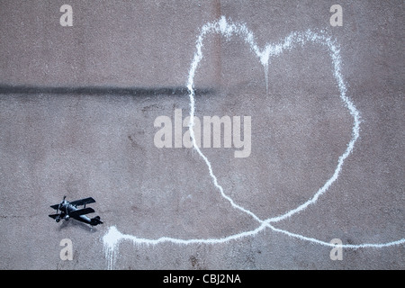 ' Piano d'amore" Nuova Banksy illustrazione, la pittura credeva di essere dall'artista di strada Banksy è comparso nel centro di Liverpool. Esso raffigura un biplano lasciando una scia di fumo, è sul muro di Rumford Street, Liverpool. È comparso durante la notte 10 Dic 2011. Foto Stock