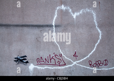 ' Piano d'amore" Nuova Banksy illustrazione, la pittura sfigurata credeva di essere dall'artista di strada Banksy è comparso nel centro di Liverpool. Esso raffigura un biplano lasciando una scia di fumo, è sulla parete di Rumford Street, Liverpool. È comparso durante la notte 10 Dic 2011. Foto Stock