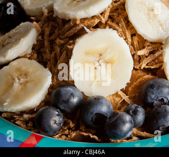 Cereali per la prima colazione con banane di mirtilli e scaglie di crusca nel recipiente Foto Stock