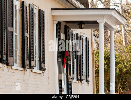 Mattoni vecchi casa coloniale decorato per il Natale con la corona sulla porta Foto Stock