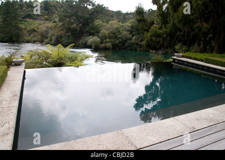 Un resort piscina infinity si trova sulle rive del fiume Waikato vicino a Cascate Huka nel Lago Taupo regione della Nuova Zelanda. Foto Stock