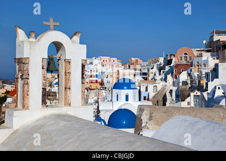 Campanile della chiesa, croce e le cupole blu nel villaggio di Oia a Santorini, Grecia Foto Stock