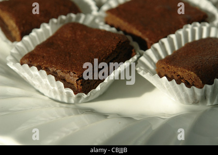 Still Life fotografia di una piastra bianca con molti strati di cioccolato brownie bianco in bicchieri di carta Foto Stock