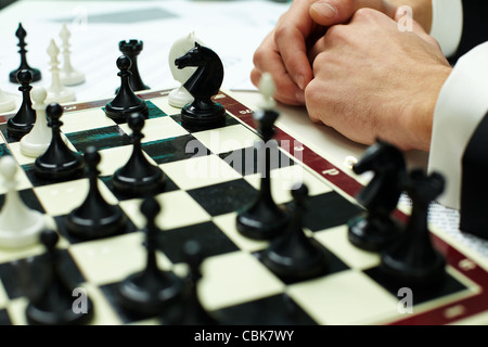 Immagine delle figure di scacchi sulla scacchiera con mani umane nelle vicinanze Foto Stock