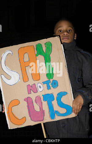 Giovane black boy tiene un cartello con scritte colorate che legge 'say no ai tagli" Foto Stock