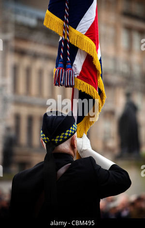 Soldato in pensione tenendo una bandiera in ricordo annuale Servizio, George Square, Glasgow, Scotland, Regno Unito, Gran Bretagna Foto Stock