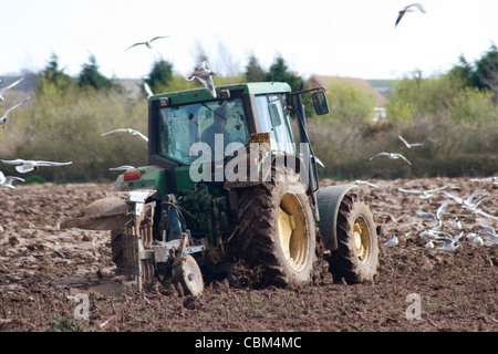 Un trattore John Deere arando un campo vicino Porchfield sull'Isola di Wight in primavera. Foto Stock