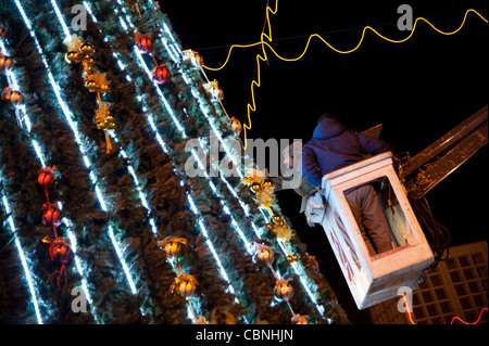 I lavoratori messi tocchi di rifinitura sull'albero di Natale che sovrasta la piazza della Mangiatoia in Cisgiordania città di Betlemme. Foto Stock