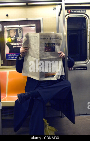 Uomo legge gli investitori quotidiano su un treno della metropolitana di New York per il suo modo di Wall Street. Foto Stock